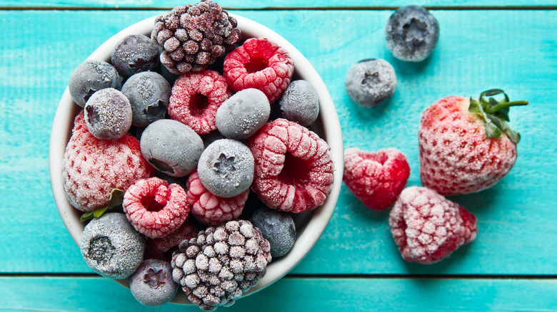 Bowl of frozen berries on blue background