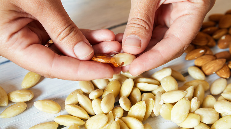 Hands peeling almonds