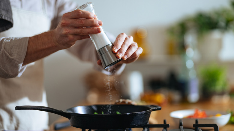 chef adding salt to skillet on stovetop
