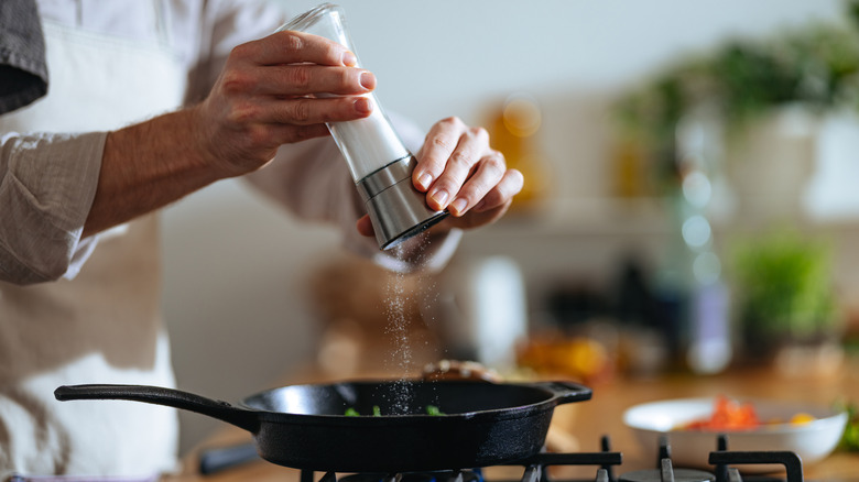 chef adding salt to skillet on stovetop
