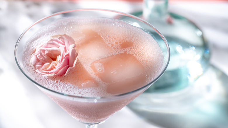 Martini glass with pink cocktail and rose