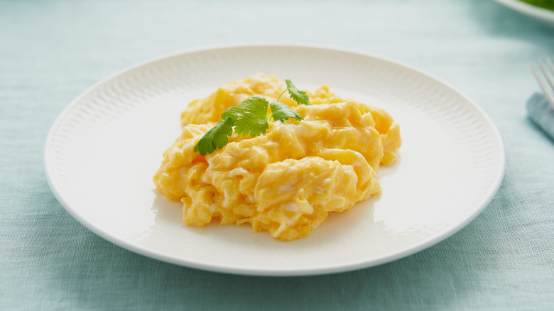 Plate of creamy scrambled eggs with sprig of parsley