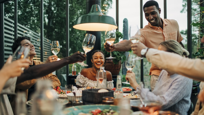 Guests gathered around a dinner table lift their glasses in a toast