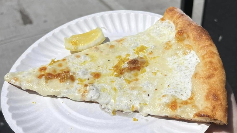 White pizza slice with lemon on paper plate