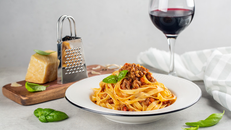 tagliatelle pasta with bolognese sauce and a glass of red wine