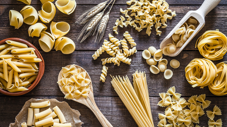 Various shapes of pasta on wood background
