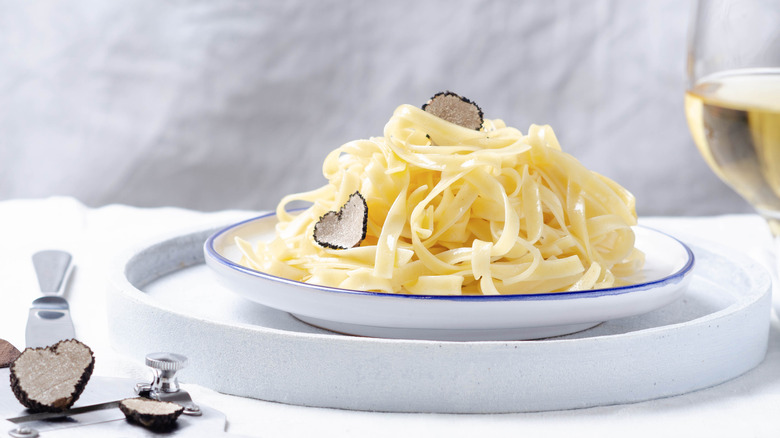 Tagliatelle pasta on white plate with shaved truffles