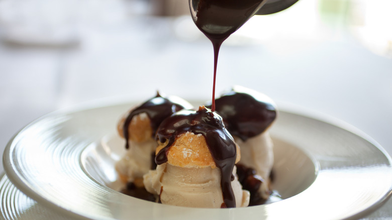 Chocolate being drizzled over profiteroles