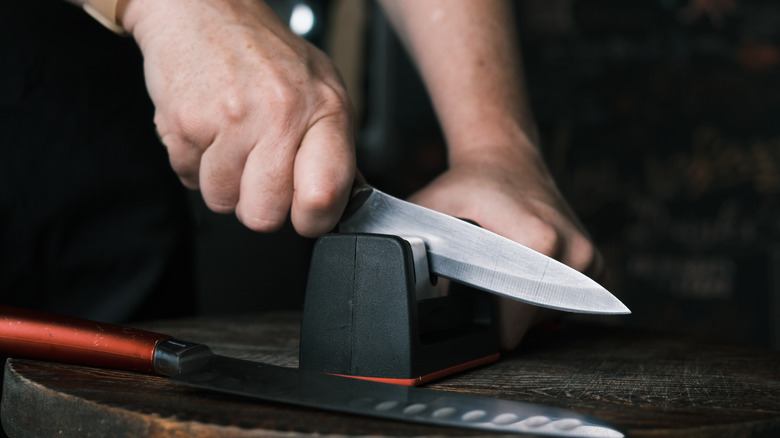 hands sharpening knives with sharpener