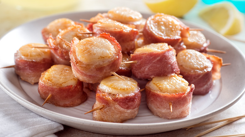 A plate of bacon-wrapped scallops with lemon