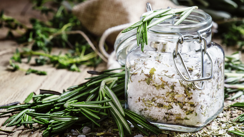Sea salt in glass jar with rosemary and herbs