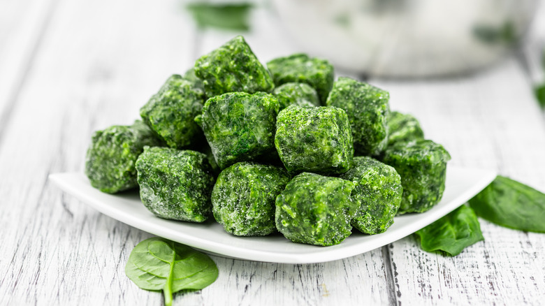 A bowl of frozen spinach cubes on a table
