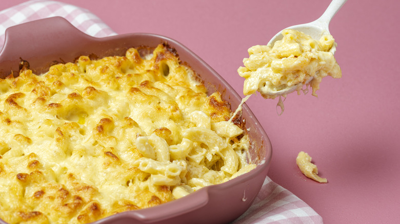 baked mac and cheese lifted out of pan with serving spoon