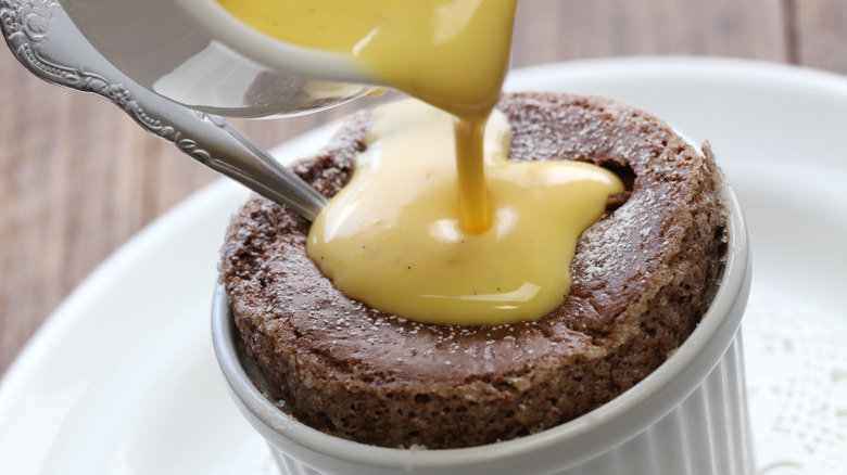 pouring creme anglaise on chocolate souflle