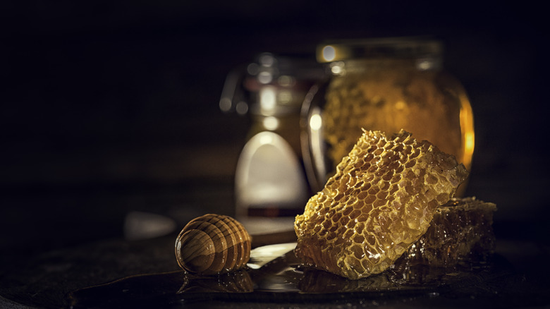 Jar of honey with honeycomb on back table
