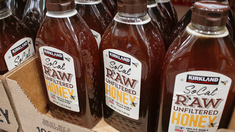 Bottles of dark raw, unfiltered Kirkland brand honey in box