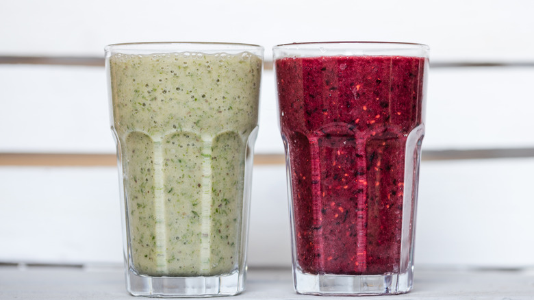 Two smoothies, one oatmeal and one berry, sit side by side on a table