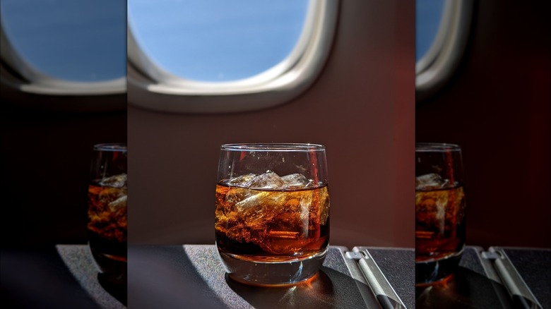 Glass full of soda and ice on airplane