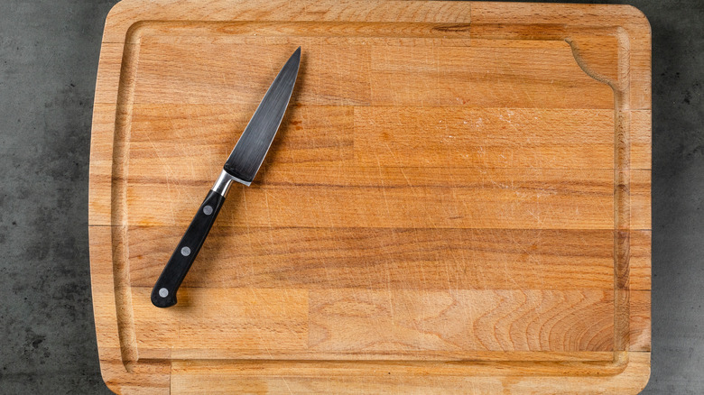 Wooden cutting board with knife on a gray surface