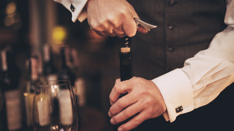 restaurant sommelier opening wine bottle