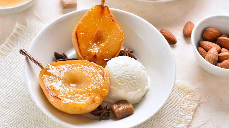 Ice cream with poached pears in bowl over light background.