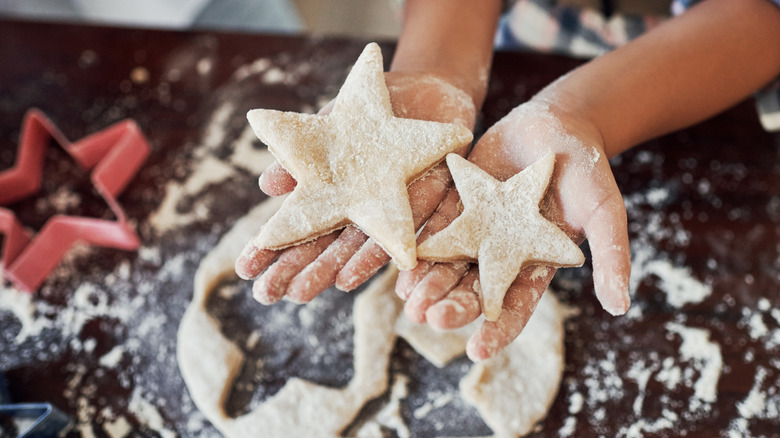 Hands holding cut out star-shaped cookie dough