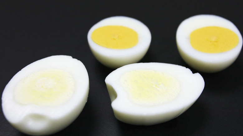 Two halves of hard-boiled eggs with yellow yolks and two halves with light yellow to white yolks.