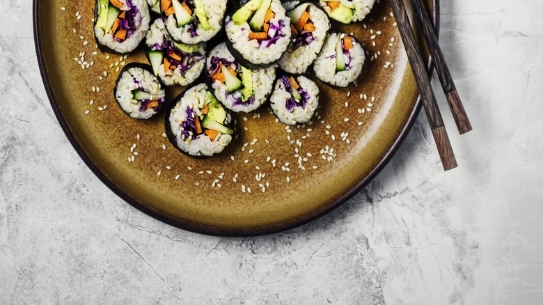 Plate of vegetarian sushi rolls with chopsticks