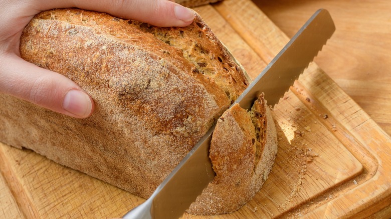 person cutting into bread loaf