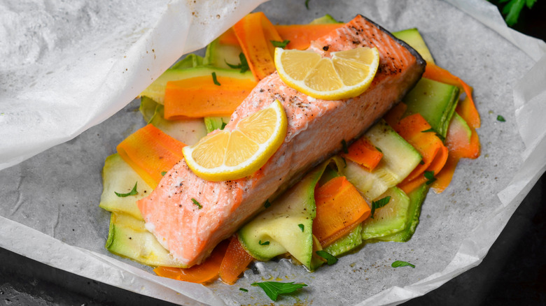 baked salmon with lemon, carrots, and zucchini on parchment paper