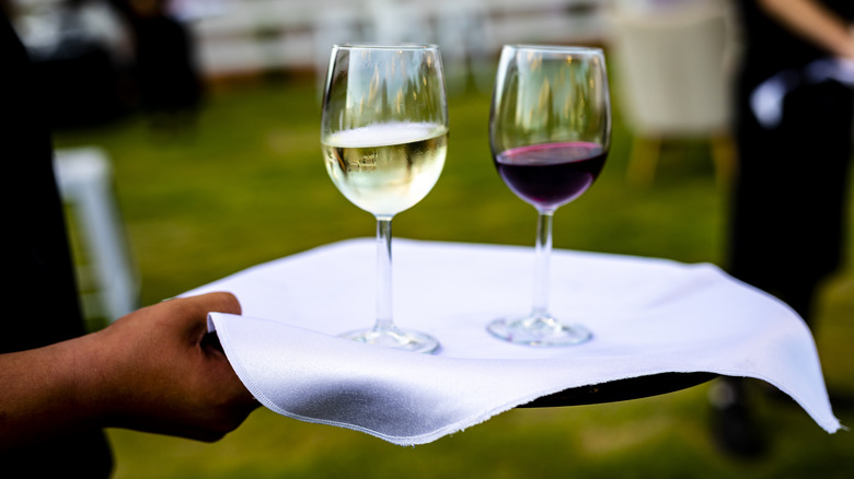 Hand serving glasses of red and white wine