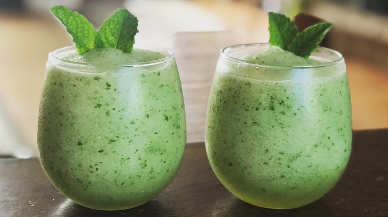 Two glasses with green slushy mint lemonade