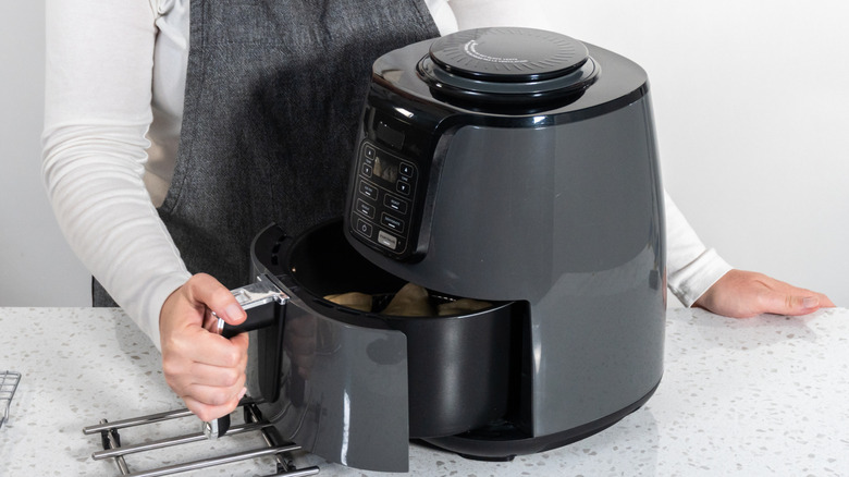 Person pulling out the basket of an air fryer