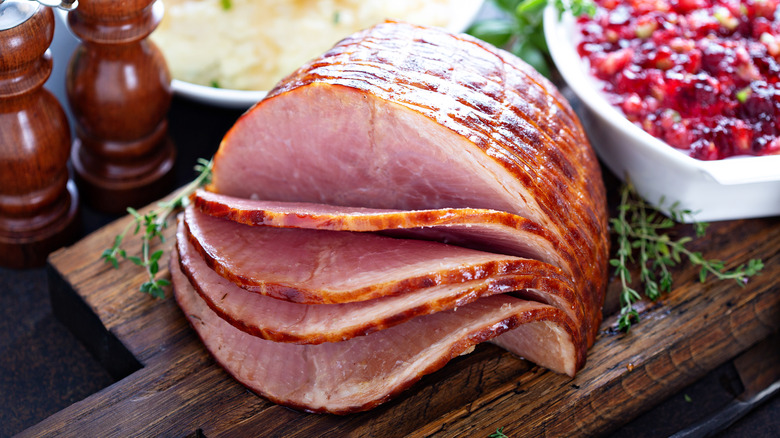 A partially sliced honey ham on a holiday table