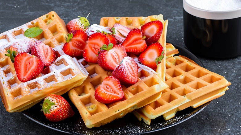 Fluffy waffles with strawberries and powdered sugar