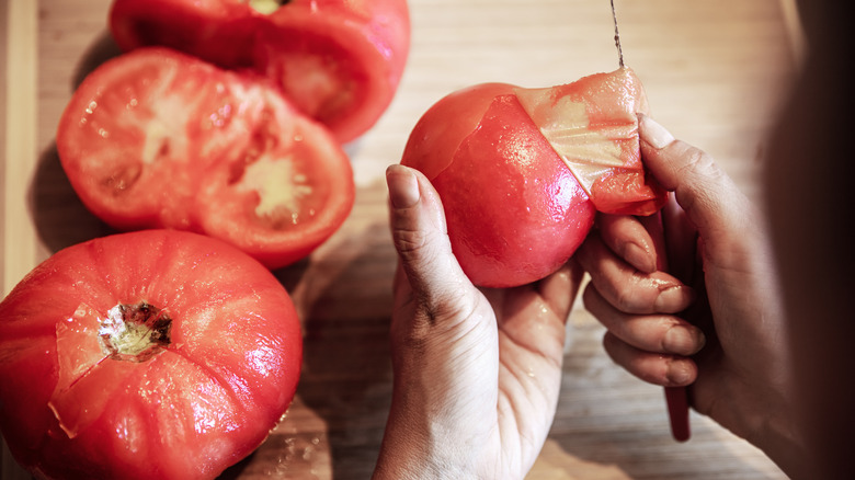 woman peeling skin from tomato