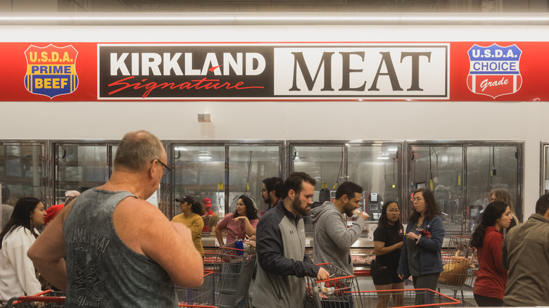 Shoppers push carts around a Costco meat department