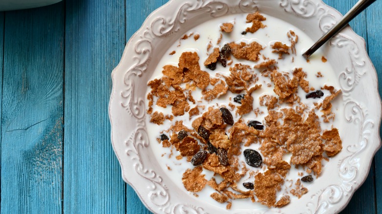 Raisin bran cereal and milk in white vintage bowl