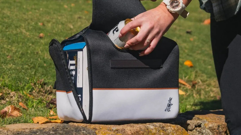 Hand placing can of beer into Kanga-brand black Kase Mate cooler