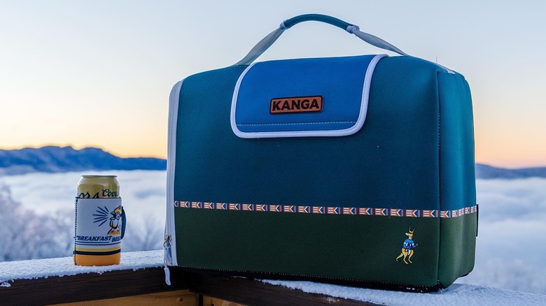 Blue Kanga Kase Mate cooler next to can of beer in a koozie