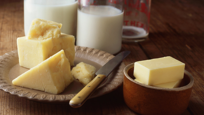 A block of firm cheese next to a bowl of rectangular butter