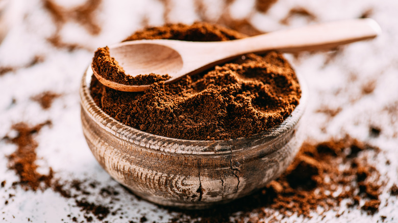 Coffee grounds in decorative wooden bowl with spoon