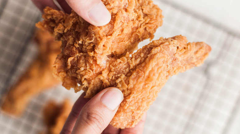 hands holding fried chicken