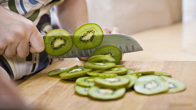 Person slicing kiwi with skin