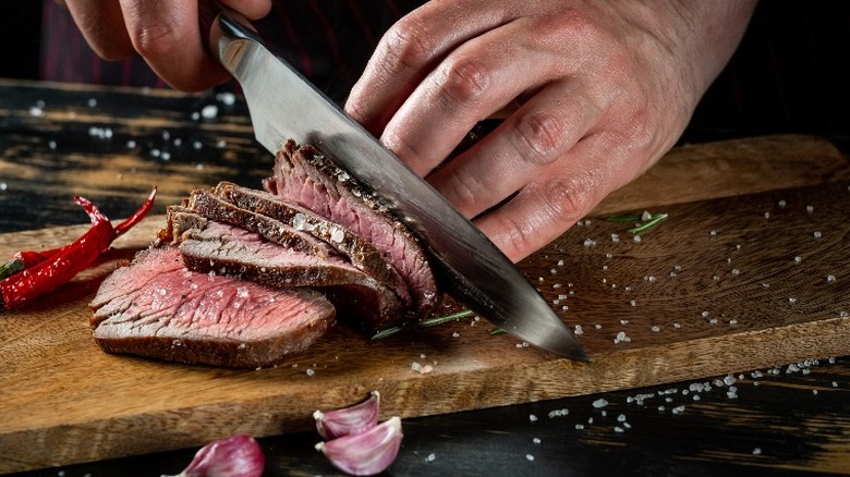 Knife cutting into steak with salt