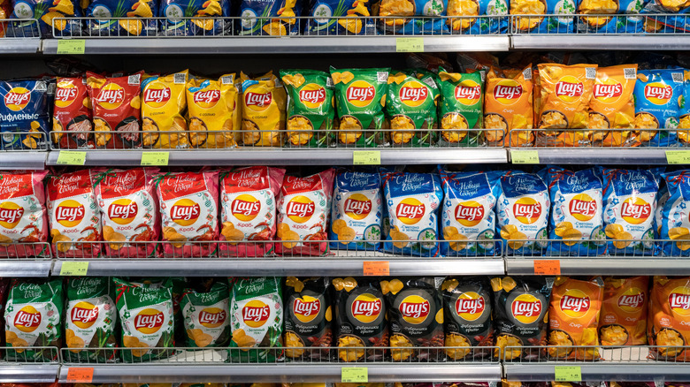 Rows of Lay's potato chips in various sizes and flavors are stocked at a grocery store