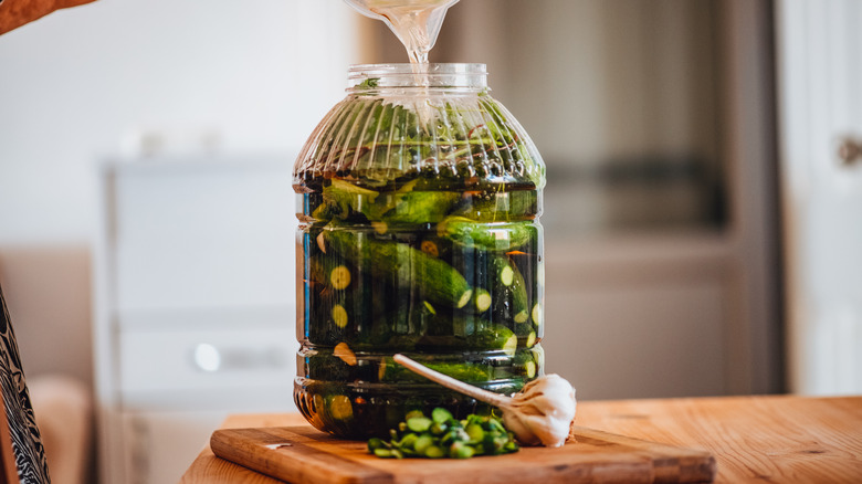 Pouring brine into jar of pickles