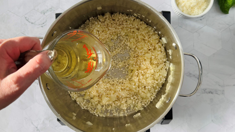 pouring wine into pot with rice and onions