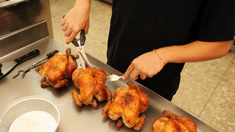chef carving chicken with scissors