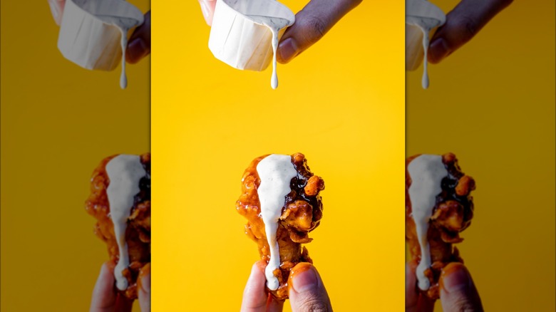 Pouring ranch on a chicken wing